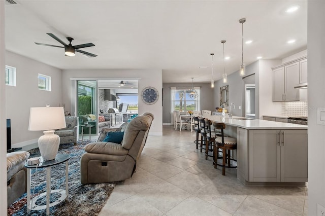 living room with ceiling fan, sink, and light tile patterned floors