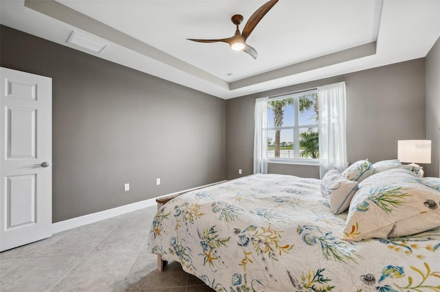 tiled bedroom with ceiling fan and a raised ceiling