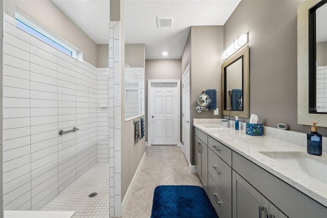 bathroom featuring tile patterned flooring, vanity, and tiled shower