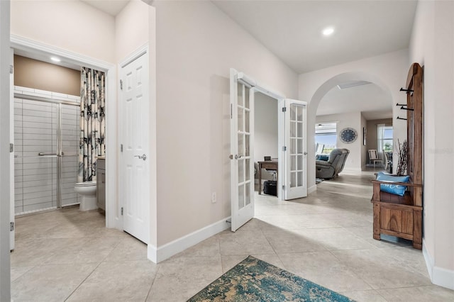 corridor featuring light tile patterned floors and french doors