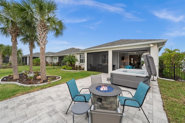 view of patio with a sunroom, a hot tub, and a fire pit