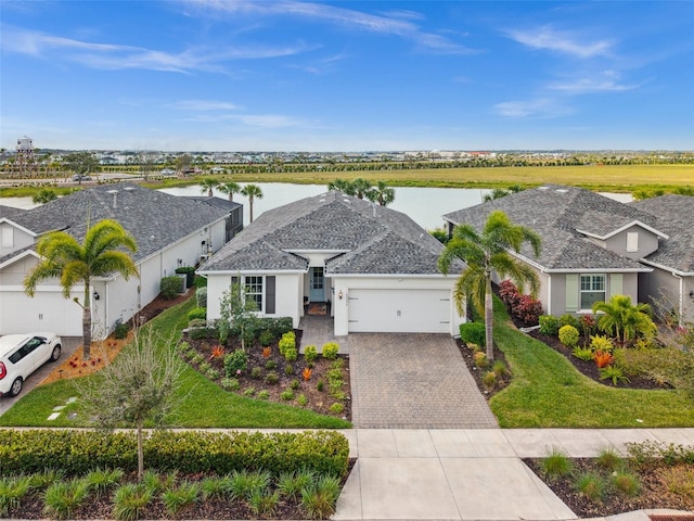 ranch-style home featuring a front yard, a garage, and a water view