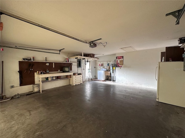 garage featuring a workshop area, a garage door opener, electric water heater, and freestanding refrigerator