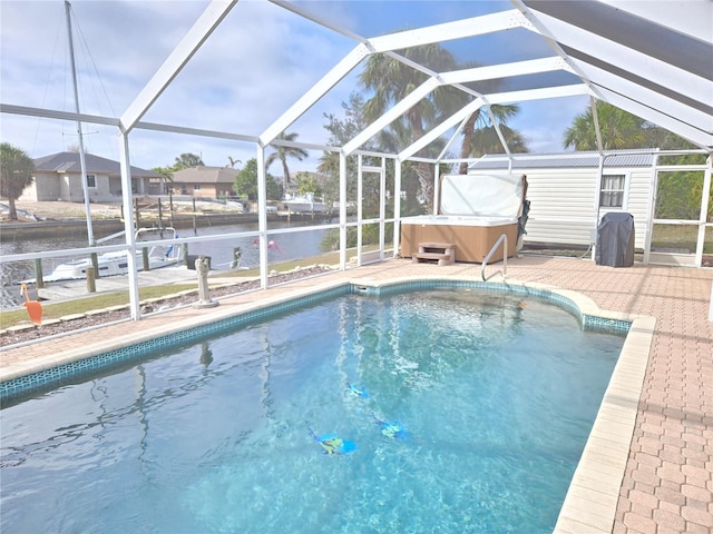 view of pool with a hot tub, a water view, glass enclosure, and a patio area