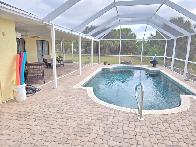 view of swimming pool with a patio, ceiling fan, and glass enclosure