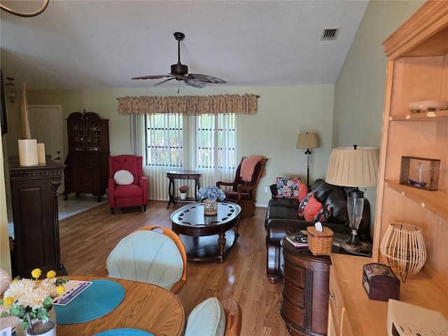 living room featuring visible vents, dark wood-type flooring, and a ceiling fan