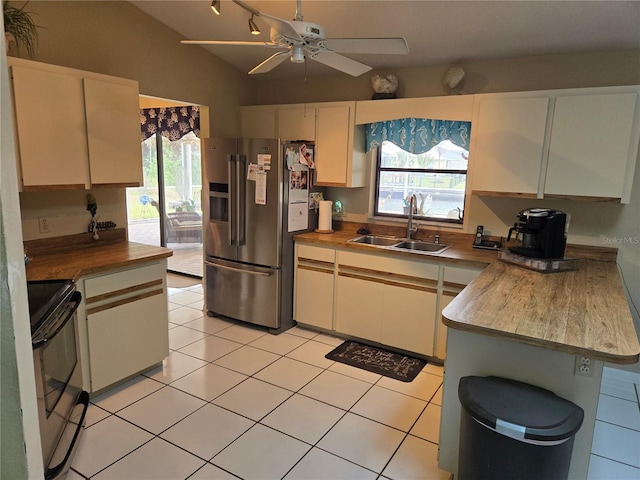 kitchen featuring range with electric stovetop, lofted ceiling, high quality fridge, a sink, and light tile patterned flooring