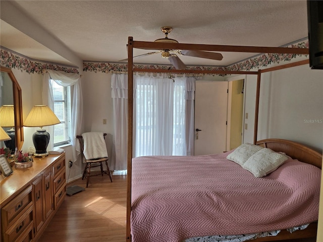 bedroom with a ceiling fan, a textured ceiling, and light wood finished floors