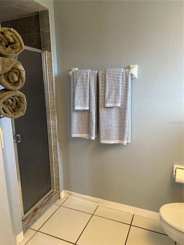 full bathroom featuring toilet, a shower stall, baseboards, and tile patterned floors