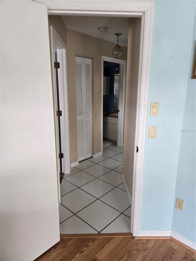 corridor featuring light tile patterned floors and baseboards