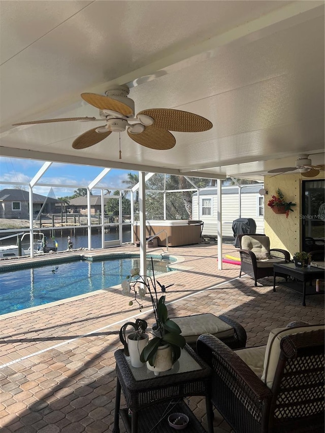 view of pool featuring a ceiling fan, a water view, a patio, and a hot tub