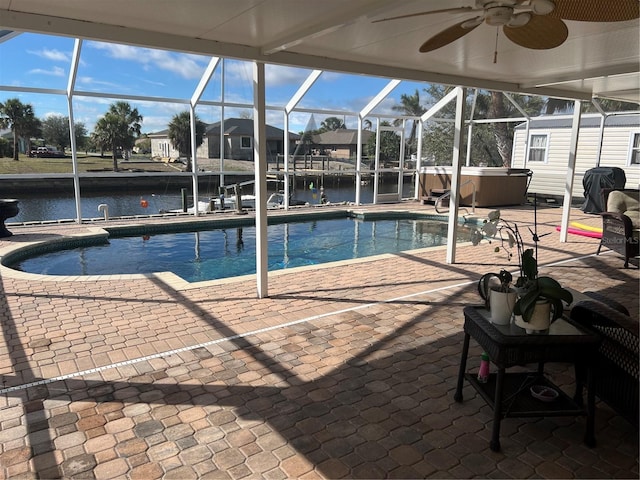 view of swimming pool featuring a ceiling fan, a patio area, a water view, and a hot tub