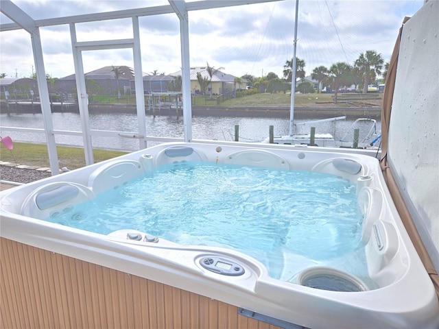 view of pool with a water view, a lanai, and a hot tub