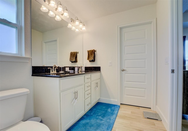 bathroom featuring toilet, hardwood / wood-style flooring, and vanity