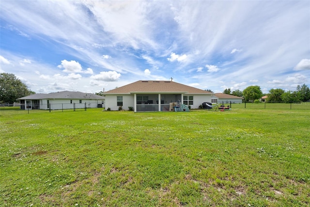 rear view of property with a yard and a sunroom