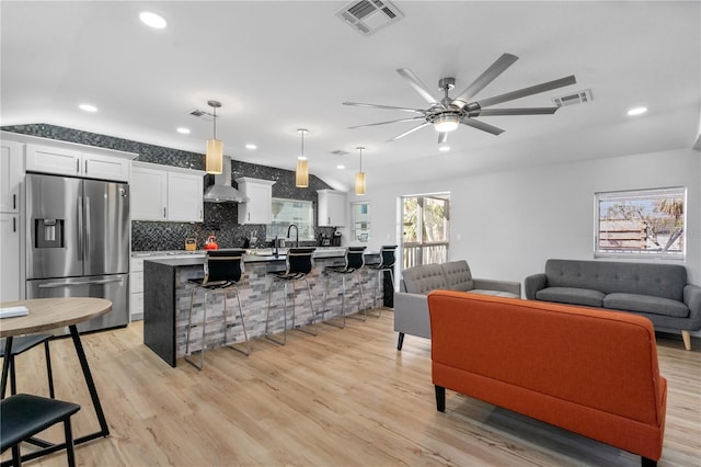 living room featuring ceiling fan, light hardwood / wood-style flooring, sink, and vaulted ceiling