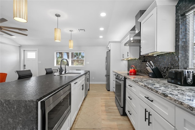 kitchen with appliances with stainless steel finishes, sink, an island with sink, and white cabinetry