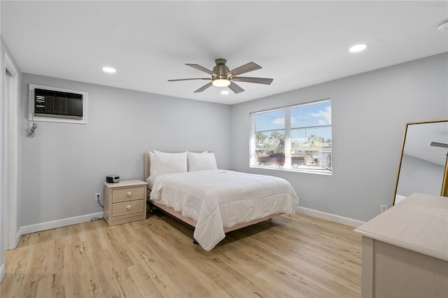 bedroom featuring ceiling fan, a wall unit AC, and light wood-type flooring