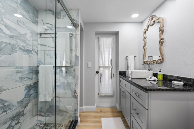 bathroom with hardwood / wood-style flooring, vanity, and a shower with door