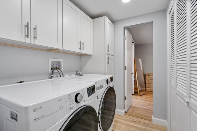 laundry room with washing machine and dryer, cabinets, and light hardwood / wood-style flooring