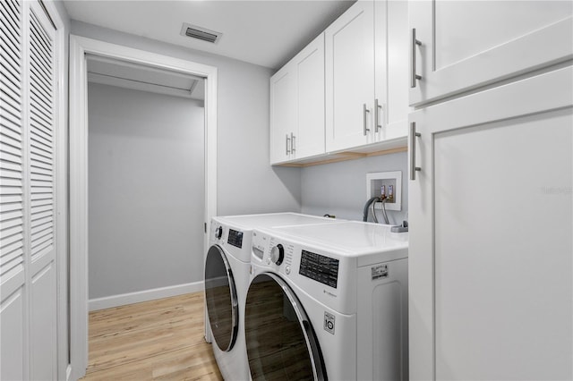 laundry room with light hardwood / wood-style flooring, separate washer and dryer, and cabinets