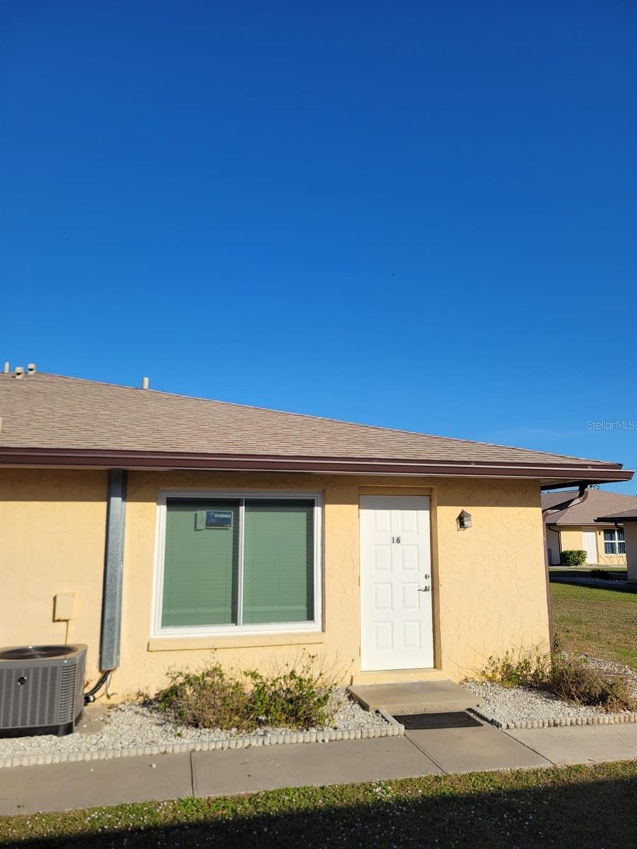 view of exterior entry featuring roof with shingles, central AC, and stucco siding