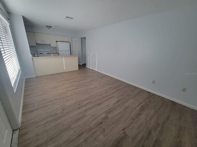 interior space with light countertops, visible vents, open floor plan, white appliances, and under cabinet range hood