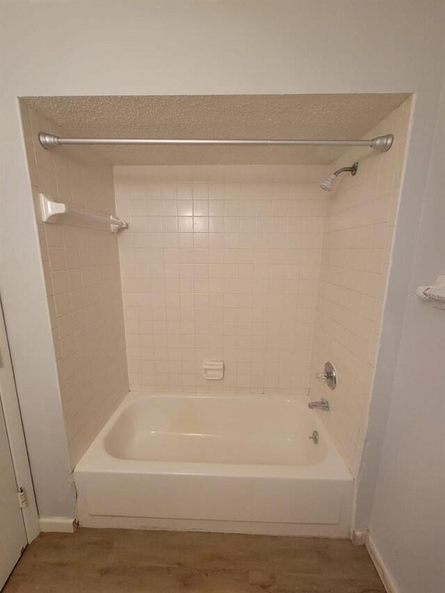 bathroom featuring  shower combination, wood finished floors, and baseboards