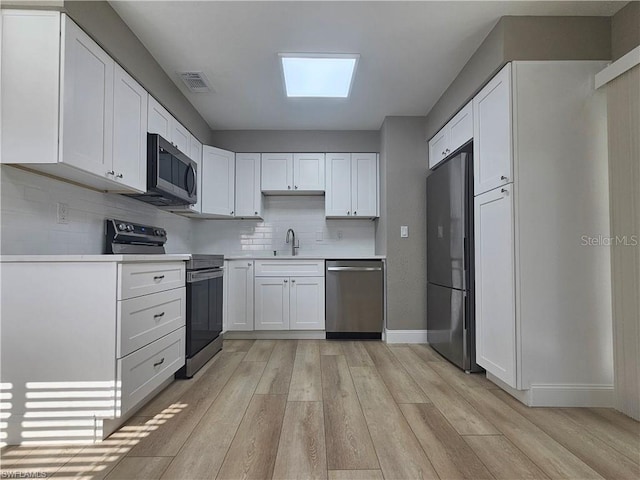 kitchen featuring light wood finished floors, visible vents, stainless steel appliances, and a sink