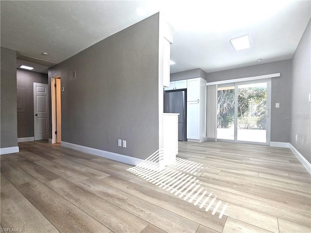 unfurnished living room with light wood-style flooring and baseboards