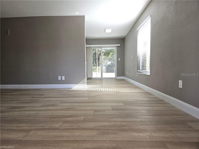 spare room with baseboards and light wood-style floors