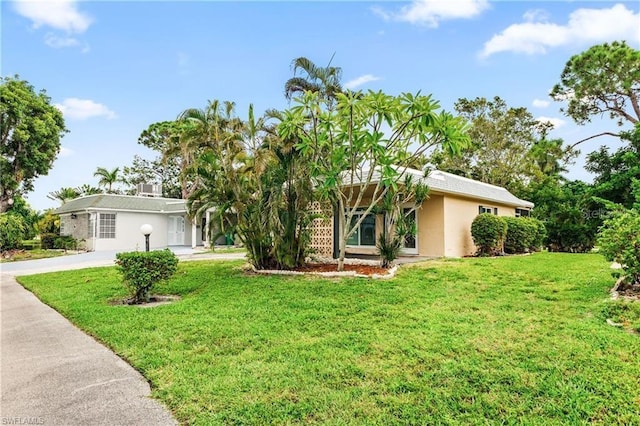 single story home featuring driveway, a front yard, and stucco siding