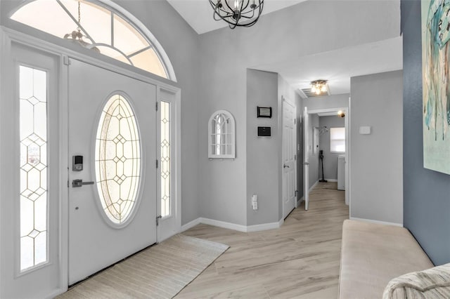 entryway with baseboards, a notable chandelier, and light wood finished floors