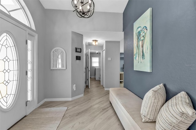 entrance foyer with a notable chandelier, light wood-type flooring, and baseboards