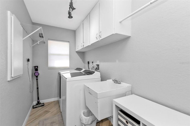 laundry area with cabinet space, light wood finished floors, baseboards, independent washer and dryer, and a sink