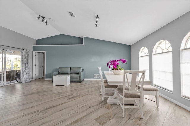 dining room featuring vaulted ceiling, light wood-style flooring, and visible vents