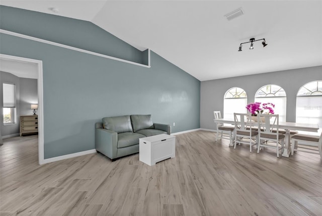 living room featuring lofted ceiling, light wood-style flooring, visible vents, and baseboards