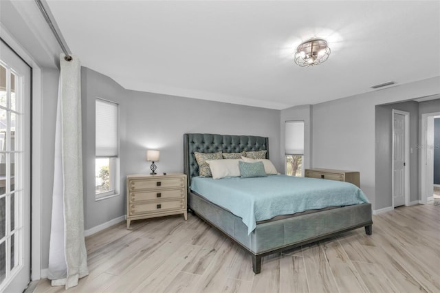 bedroom with light wood-style flooring, multiple windows, and baseboards