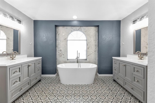 full bath featuring a freestanding bath, a textured wall, and a sink