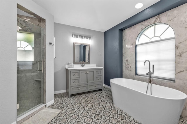 full bath featuring a stall shower, a freestanding tub, vanity, and baseboards