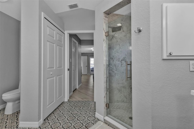 bathroom with baseboards, visible vents, toilet, a shower stall, and a closet