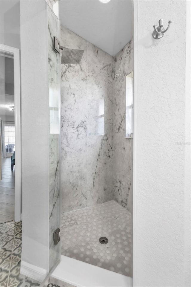 full bathroom featuring a shower stall and a textured wall