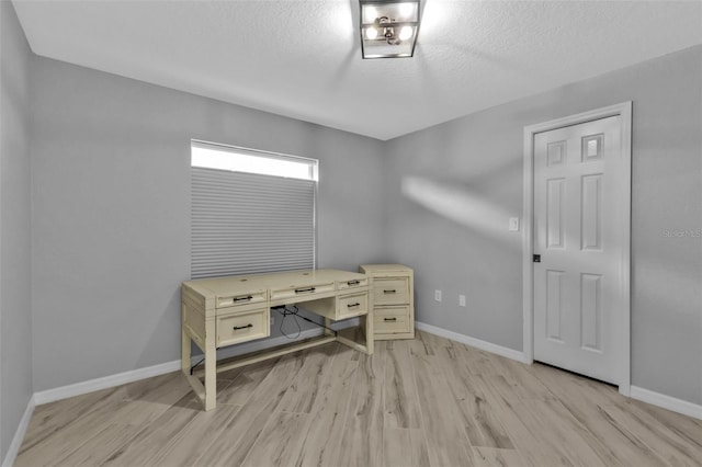 office area featuring light wood-type flooring, a textured ceiling, and baseboards