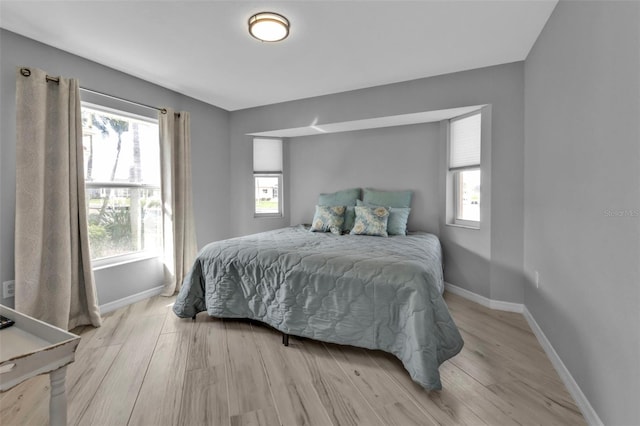 bedroom featuring light wood-style flooring, multiple windows, and baseboards