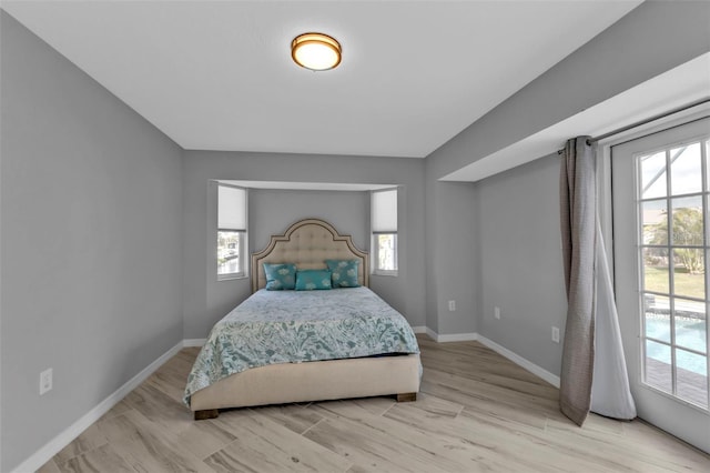 bedroom featuring baseboards, multiple windows, and light wood finished floors