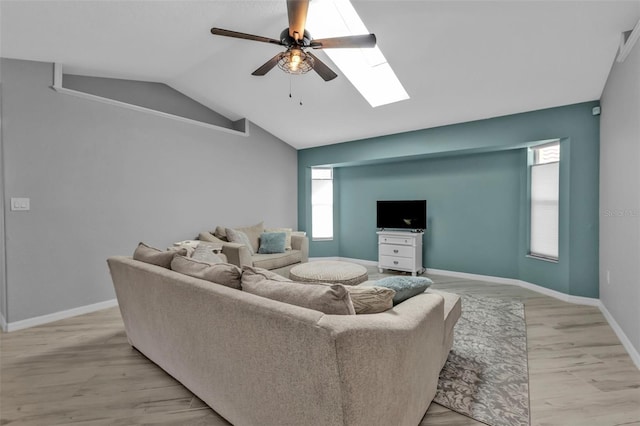 living area with light wood finished floors, lofted ceiling with skylight, a ceiling fan, and baseboards