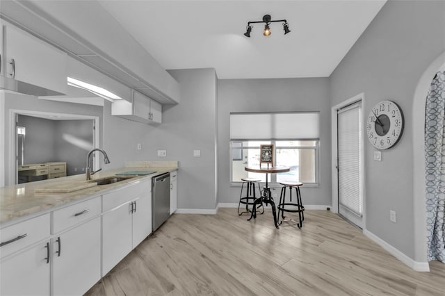 kitchen with light wood-style flooring, white cabinets, a sink, dishwasher, and baseboards