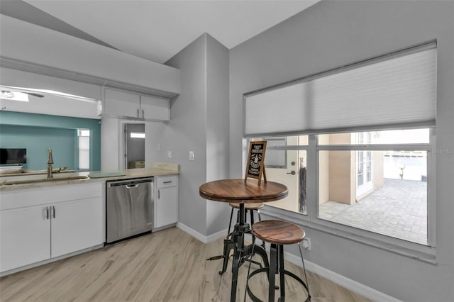 kitchen featuring light wood finished floors, light countertops, white cabinets, a sink, and dishwasher