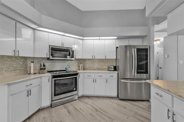 kitchen featuring stainless steel appliances, white cabinetry, and decorative backsplash