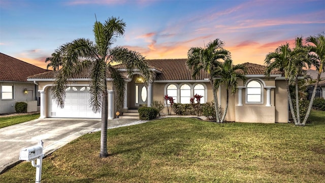 mediterranean / spanish home with a garage, concrete driveway, a lawn, and stucco siding